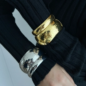 Metallic liquid-style cuff bracelets in gold and silver finish with textured surface