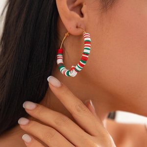 Close-up of tricolor Christmas hoop earrings with Santa charm on a female model
