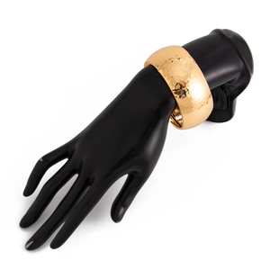 Detailed macro view of gold water ripple metal wide cuff bracelet on a black display model