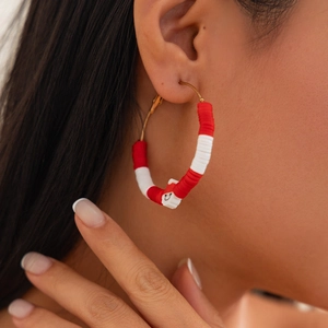 Detail of bohemian gold hoop earring with red and white heishi beads and smiley face charm