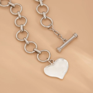 Dettaglio macro del ciondolo a cuore argento con chiusura OT e catena a maglie