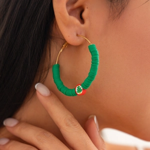 Close-up of handmade Christmas hoop earrings with green heishi beads on a model