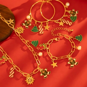 Set di gioielli natalizi con ciondoli smaltati ad albero e fiocco su sfondo rosso