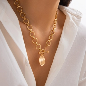 Dettaglio collana a catena dorata con chiusura a ginocchiera OT e pendente ovale su modella