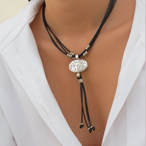 Detail of bohemian vintage necklace with textured silver pendant and beaded black cord