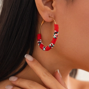 Macro shot of large gold hoop earrings with red, white and green polymer clay disc details