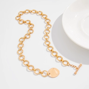 Dettaglio della collana a cuore dorata con chiusura a T e ciondolo rotondo lucido