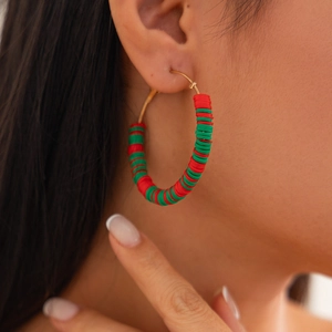 Close-up of polymer clay hoop earrings with red and green beads for Christmas styling