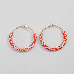 Detailed view of Christmas hoop earrings with red and white clay beads on gold rings