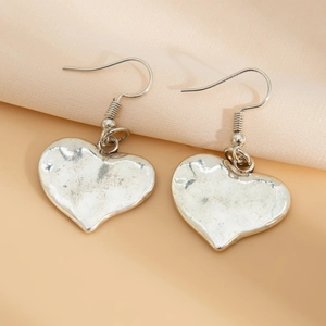 Dettaglio macro di orecchini a cuore in argento vintage con superficie metallica strutturata
