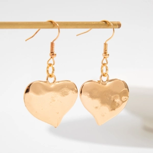 Dettaglio di orecchini a cuore in oro con trama irregolare effetto lava martellata