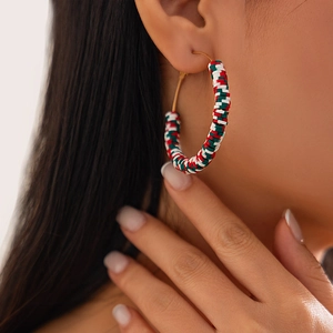 Close-up of red, white and green Heishi beads on large hoop earrings worn by a model