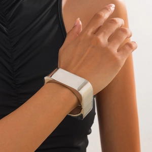 Close-up of a wide silver geometric metal bracelet with a polished mirror finish on wrist