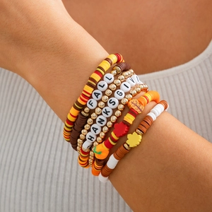 Detail of layered Thanksgiving bracelets with colorful clay beads and pumpkin charms