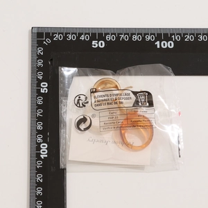 Afmetingen van de gouden C-vormige oorbellen en de barnsteenhars ring op wit canvas