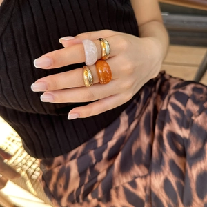 Detail van vierdelige modieuze ringenset met goud metaal en amber hars op een modelhand