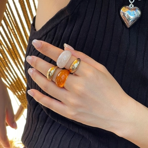 Detail van modieuze sieradenset met goudkleurige metalen ringen en amberkleurige harsring