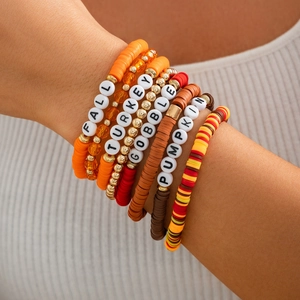 Close-up of stacked Thanksgiving bracelets with turkey and pumpkin letter beads
