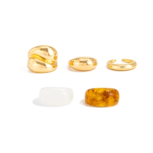 Detailopname van amberkleurige hars en gouden metalen ringenset op wit