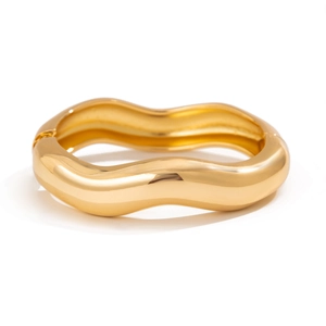 Detailed view of wide gold wave bangle with chunky curved design and side hinge clasp