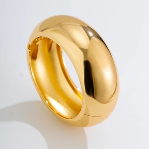 Detailed macro view of the polished golden wide bangle with a smooth mirror finish