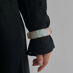 Brazalete ancho irisado con textura orgánica sobre muñeca con manga negra