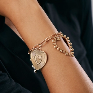 Detail of chunky gold chain bracelet with solid radiant and hollow beaded heart charms