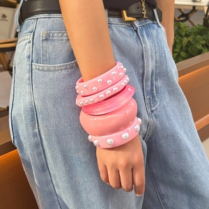 Set de brazaletes de resina rosa con perlas y diseño ancho estilo dopamina en modelo