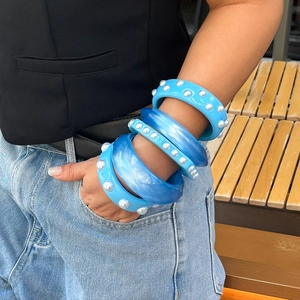 Set de 4 brazaletes de resina azul con perlas y textura de mármol en la muñeca