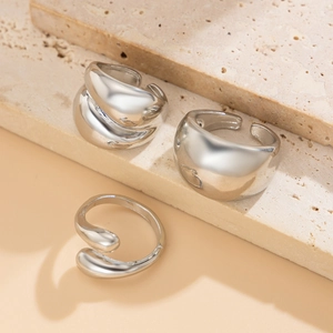 Détail de trois bagues ouvertes argentées au design goutte d'eau minimaliste sur pierre