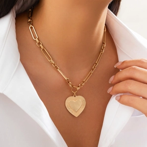 Close-up of golden lava heart pendant necklace with textured detail on white shirt