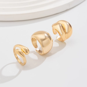 Trois bagues et boucles d'oreilles minimalistes en or sur fond blanc épuré