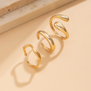 Détail d'une bague goutte d'eau dorée et de boucles d'oreilles vagues sur pierre