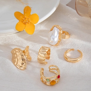 Detail of a 6-piece gold-tone ring set featuring floral, baroque pearl, and hammered textures
