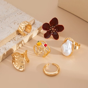 Close-up of golden lava rings collection with baroque pearls and floral enamel detail