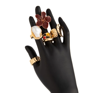 Detail shot of five unique gold rings with baroque pearl and red flower on a black hand