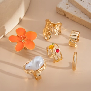 Detailed set of six vintage gold rings featuring pearls, floral motifs, and colorful gemstones
