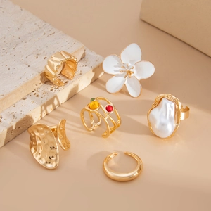Detailed view of 6pcs gold flower and baroque pearl ring set on natural stone stand