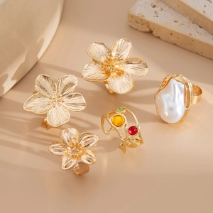 Detailed close-up of gold flower rings with baroque pearls and colorful gemstones