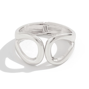 Detail of silver hollow cuff bracelet with oval cutouts and polished spring hinge mechanism