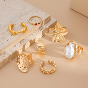 Detailed close-up of 7-piece gold ring set featuring baroque pearls and floral designs