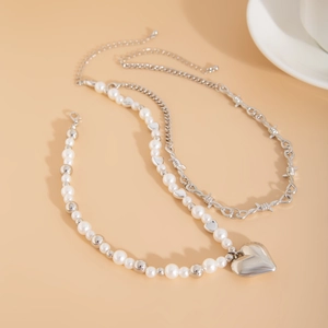 Detailed view of layered pearl heart necklace with silver thorny metal chain link