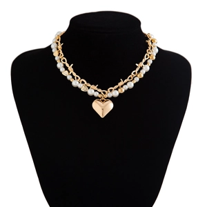 Detailed close-up of double-layer necklace with pearl beads and gold heart pendant