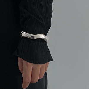 Macro detail of silver-toned irregular wave cuff bracelet with high-shine mirror finish