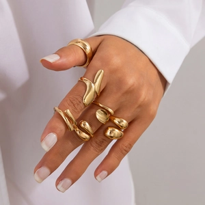 Détail de bagues gouttes d'or superposées et anneau en métal liquide sur main femme