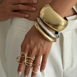 Bracciali rigidi in oro e argento con anelli minimalisti indossati dalla modella