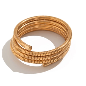 Macro view of minimalist layered gold spiral coil bracelet with reflective metallic finish
