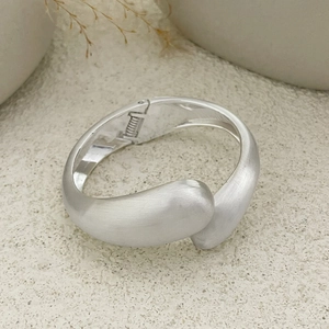 Detail view of matte brushed silver metal bangle with hinge and stylish drop shape