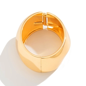 Detailed macro view of golden hinged wide bangle with polished mirror finish texture