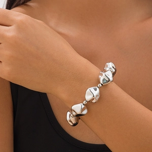 Primer plano de un brazalete de metal líquido plateado con texturas de perlas únicas